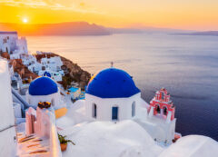 The iconic blue domes and whitewashed houses of Oia at golden hour.